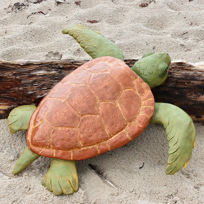 Sea turtle sculpture leaning on drift wood.