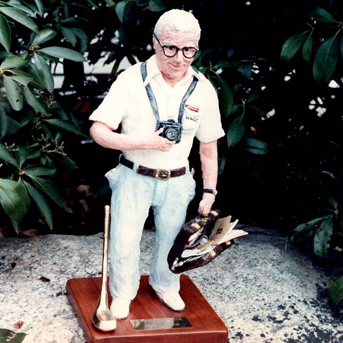 Sculpture of a man holding a camera and a briefcase full of items